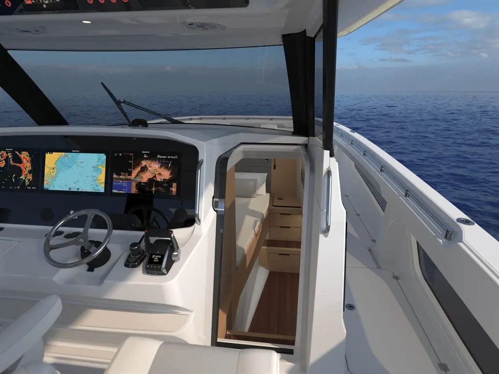 Boat cockpit view with navigational screens, steering wheel, and doorway leading below deck; blue ocean in background.